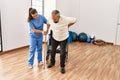 Senior man sitting on wheelchair being assited by geriatric nurse, handicapped mature man getting help to stand up Royalty Free Stock Photo