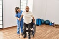 Senior man sitting on wheelchair being assited by geriatric nurse, handicapped mature man getting help to stand up Royalty Free Stock Photo