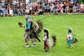 Senior man and small native boys dressed in ceremonial costume for the annual pow wow dancing in an arena