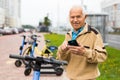 Senior man with smartphone activating electric scooter