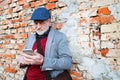 Senior man with smartphone against brick wall, texting. Royalty Free Stock Photo