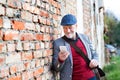 Senior man with smartphone against brick wall, texting. Royalty Free Stock Photo