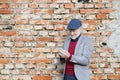 Senior man with smartphone against brick wall, texting. Royalty Free Stock Photo