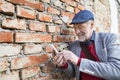 Senior man with smartphone against brick wall, texting. Royalty Free Stock Photo