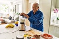 Senior man smiling confident shaking blender at kitchen Royalty Free Stock Photo