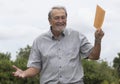 Senior Man Smiling Holding Manilla Envelope