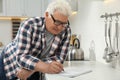 Senior man solving sudoku puzzle at kitchen Royalty Free Stock Photo