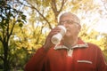 Senior man in sports clothing standing in park and drink Royalty Free Stock Photo