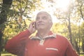 Senior man in sports clothing standing in park and talki