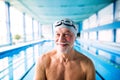 Senior man standing in an indoor swimming pool.