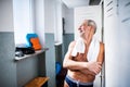 Senior man standing by the lockers in an indoor swimming pool. Royalty Free Stock Photo