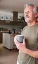 Senior Man Standing And Looking Out Of Kitchen Door Drinking Coffee Royalty Free Stock Photo