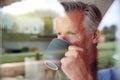 Senior Man Standing And Looking Out Of Kitchen Door Drinking Coffee Viewed Through Window Royalty Free Stock Photo