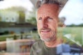 Senior Man Standing And Looking Out Of Kitchen Door Viewed Through Window Royalty Free Stock Photo