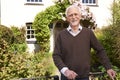 Senior Man Standing Outside Pretty Cottage