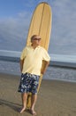 Senior Man Standing With Surfboard At Beach Royalty Free Stock Photo