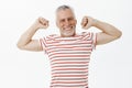 Senior man stretching after good job feeling happy and energized living active life of pensioner wearing striped t-shirt