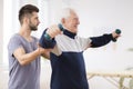 Senior man after stroke at nursing home exercising with professional physiotherapist