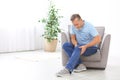 Senior man suffering from knee pain in living room. Royalty Free Stock Photo