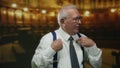 Senior man in a suit gestures confidently while speaking inside a dimly lit church, emphasizing his points with expressive hand Royalty Free Stock Photo