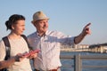 Senior man in summer hat shows the way on the map to young woman. Royalty Free Stock Photo
