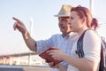 Senior man in summer hat shows the way on the map to young woman. Royalty Free Stock Photo