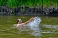 Senior man swimming in the taiga Siberian river Vagai, Russia