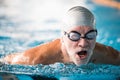 Senior man swimming in an indoor swimming pool. Royalty Free Stock Photo