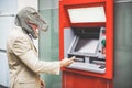Senior man with t-rex mask withdraw money from bank cash machine with debit card - Crazy new trends advertising concept - Focus on