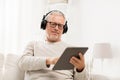 Senior man with tablet pc and headphones at home Royalty Free Stock Photo