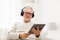 Senior man with tablet pc and headphones at home Royalty Free Stock Photo