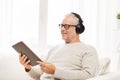 Senior man with tablet pc and headphones at home Royalty Free Stock Photo