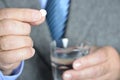 A senior man taking medicine with a glass of water.