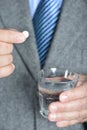 A senior man taking medicine with a glass of water.