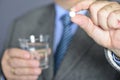 A senior man taking medicine with a glass of water.