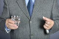 A senior man taking medicine with a glass of water.