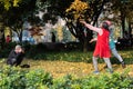 Senior man taking photos of two women throwing yellow gingko tree leaves