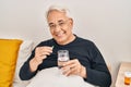 Senior man taking pill sitting on bed at bedroom Royalty Free Stock Photo