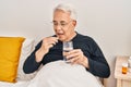 Senior man taking pill sitting on bed at bedroom Royalty Free Stock Photo