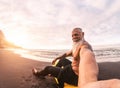 Senior man taking selfie in surfing day - Mature hipster male having fun doing surf at sunset time Royalty Free Stock Photo