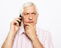 Senior man talking on mobile phone, doubts, difficult choice, touches chin with hand