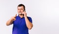 The senior man talks on the smartphone and points his index finger at the camera. Gray background and empty side ad Royalty Free Stock Photo