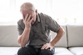 Senior man thinking and sitting on sofa at home like sad