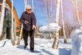 Senior man throwing snow with shovel from private house yard in winter on bright sunny day. Elderly person removing snow in garden Royalty Free Stock Photo