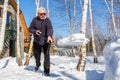 Senior man throwing snow with shovel from private house yard in winter on bright sunny day. Elderly person removing snow in garden Royalty Free Stock Photo