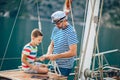 Senior man tying knot and securing with grandson on yacht sail boat
