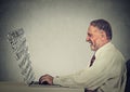 Senior man typing on his laptop computer with screen made of alphabet letters Royalty Free Stock Photo