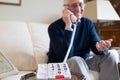 Senior Man Using Telephone With Oversized Keypad At Home