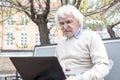 Senior man using laptop computer outdoors Royalty Free Stock Photo