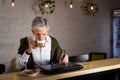 Senior man using laptop and having coffee in the bar Royalty Free Stock Photo